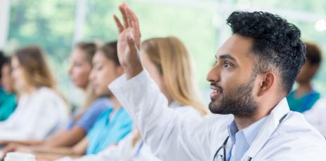 an adult student raising their hand inside a classroom with other adult learners