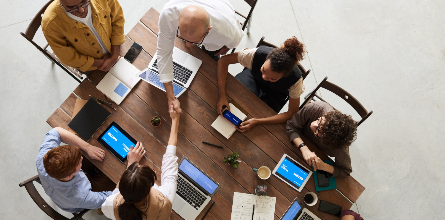 overhead shot of coworkers gathered around a table with laptops and tablets