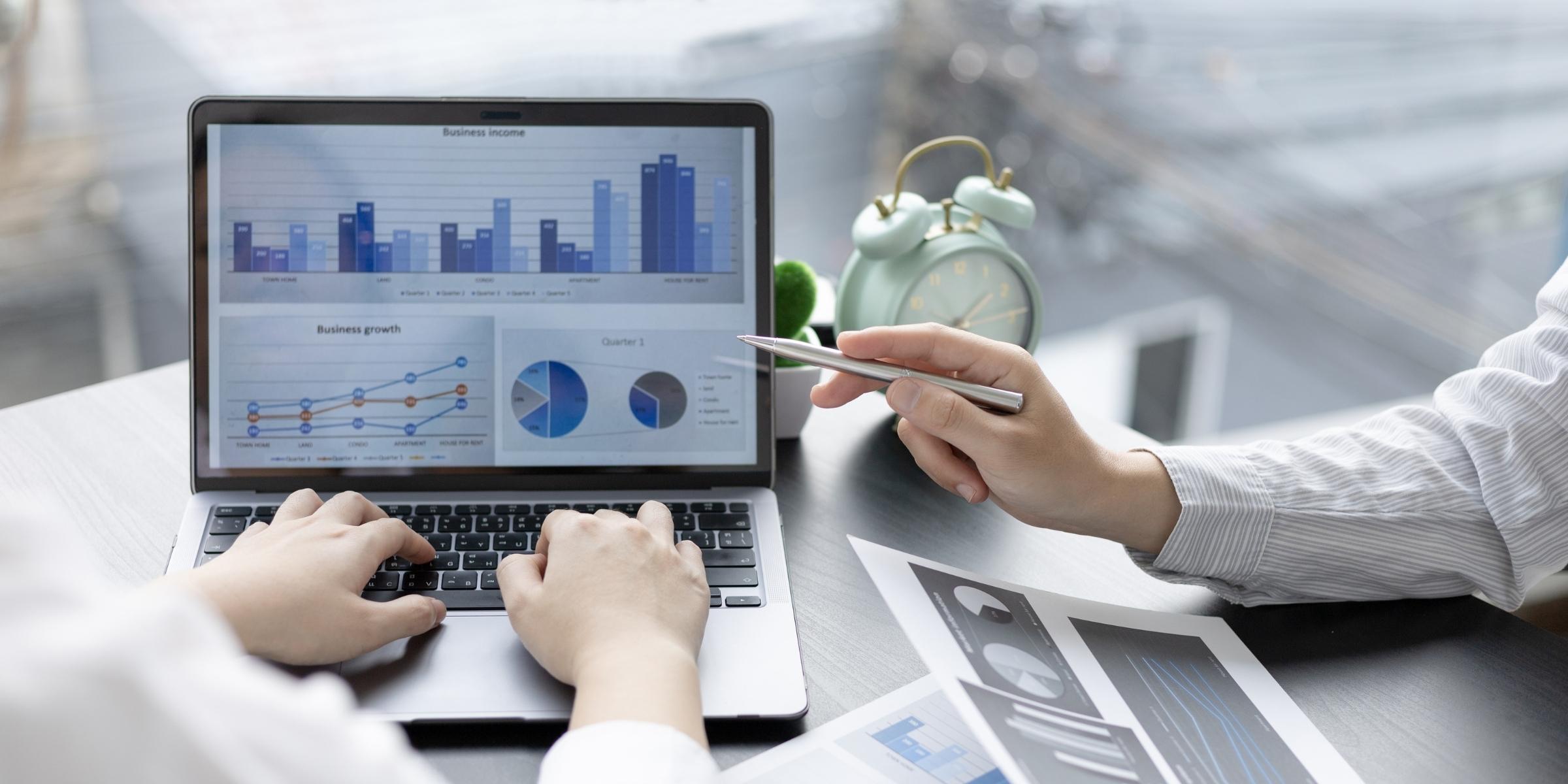 a data dashboard shown on a laptop with two sets of hands near it