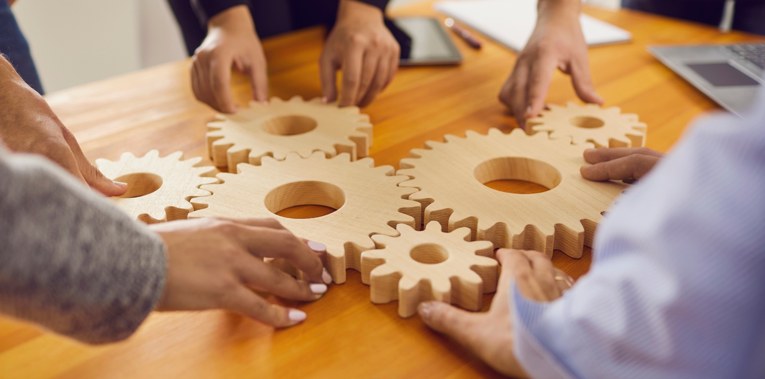 hands on a table putting together wooden cogs 