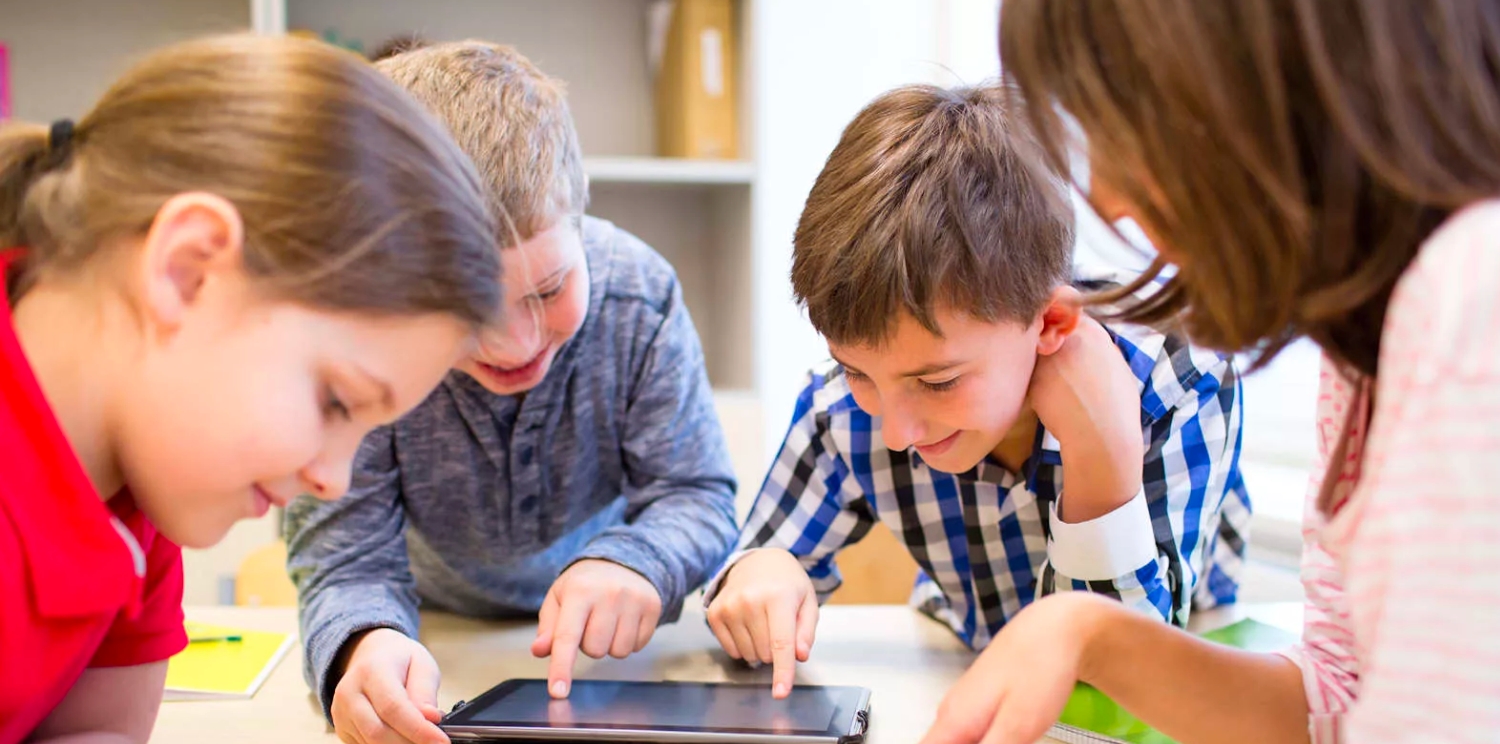 a group of young kids playing with a mobile tablet