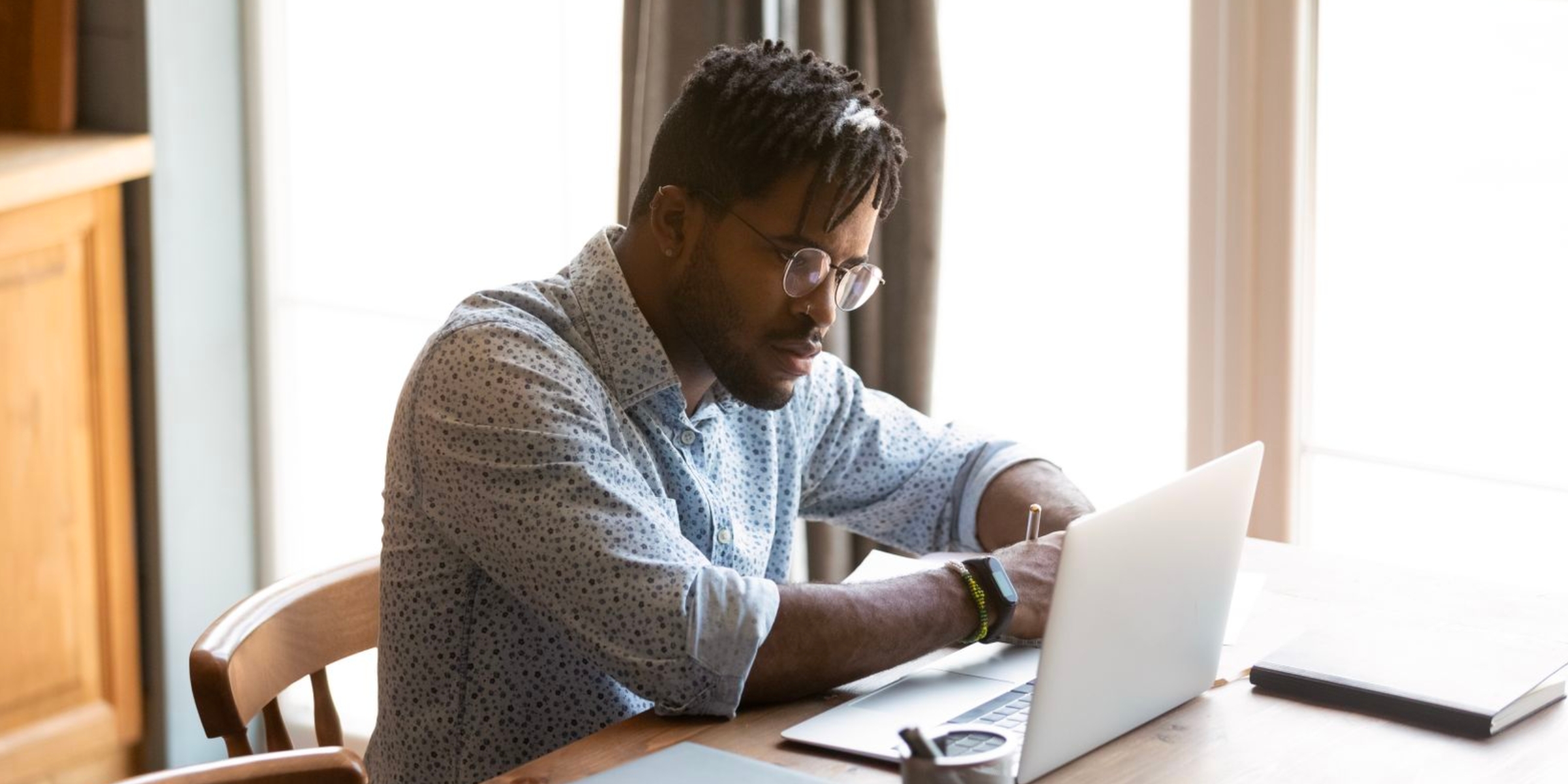 a student taking notes in front of a laptop