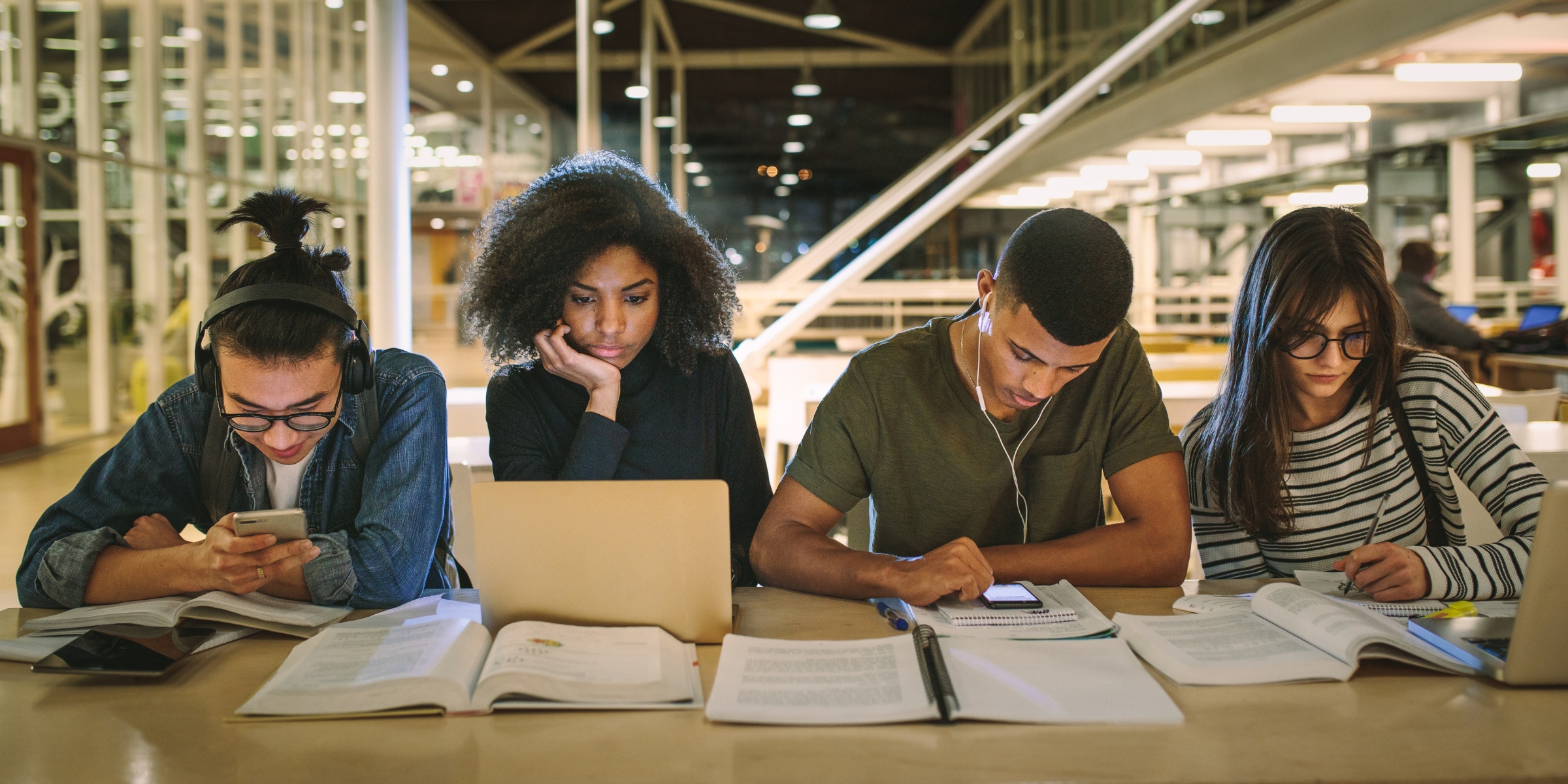 four students studying at a table inside a college library