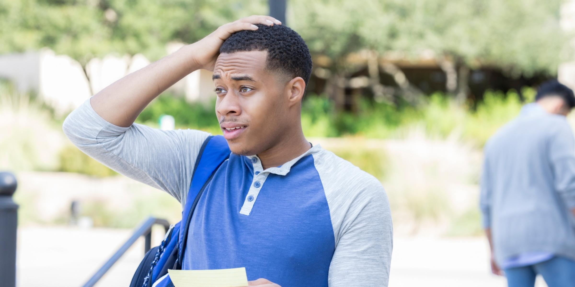 a student looking off to the side, with a hand on their head, looking confused